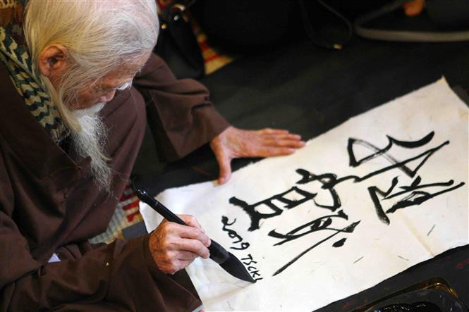 Viejo maestro escribe letras caligráficas. (Fuente: VNA)