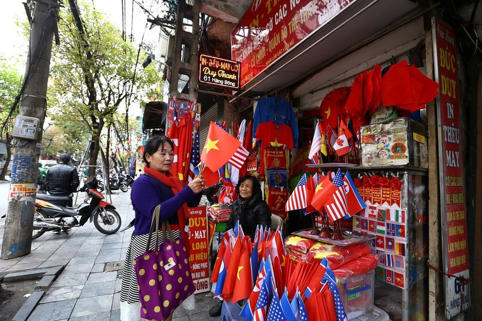 Los turistas compran banderas de EE.UU., Corea del Norte y Vietnam en la calle Hang Bong, Hanoi. (Foto: VNA)