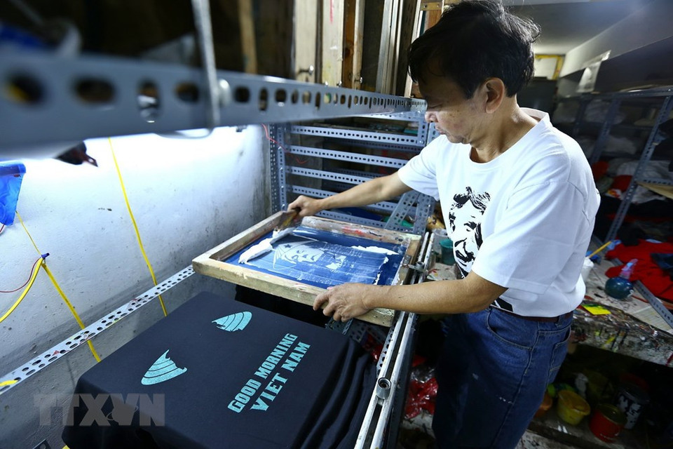 En estos días, en el taller de impresión de camisetas de Truong Thanh Duc en la calle Hang Bong se imprimen más de 300 unidades por día. (Foto: VNA)
