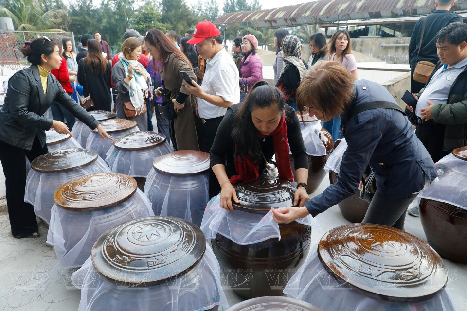 Turistas visitan una fábrica de salsa de almejas en Con Den. (Foto: VNA)