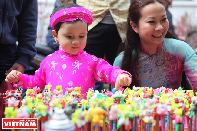 Niña en vestida tradicional acompaña a su madre en la calle Hang Luoc. 