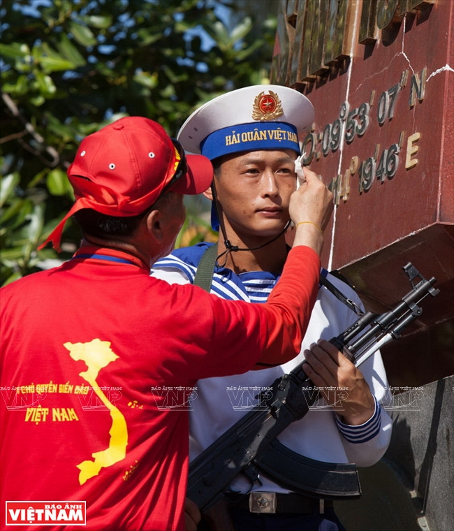 Un coterráneo residente en Sudcorea seca sudor a un combatiente que guarda un hito de demarcación territorial en la isla Sinh Ton. 