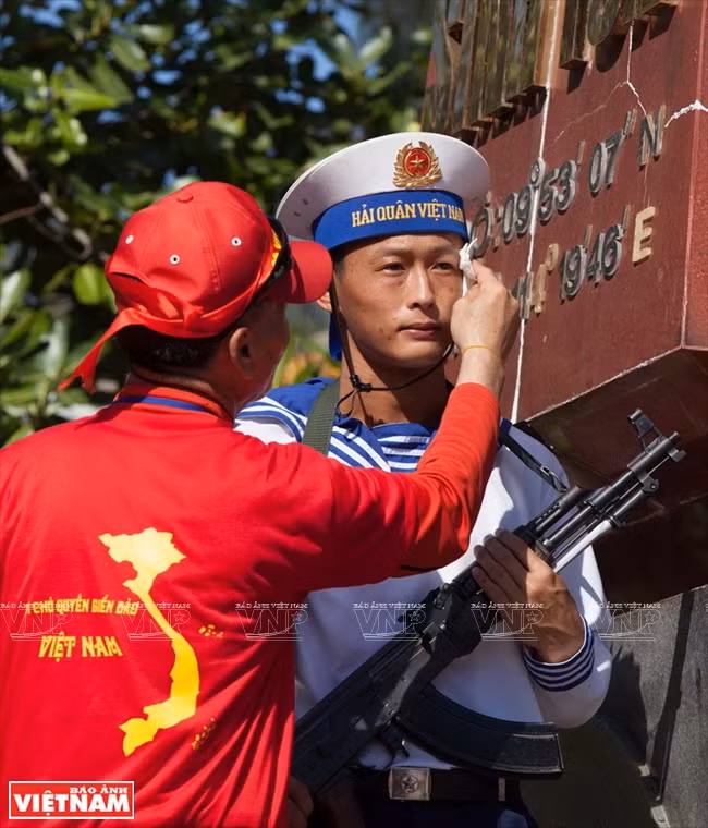 Un coterráneo residente en Sudcorea seca sudor a un combatiente que guarda un hito de demarcación territorial en la isla Sinh Ton. 