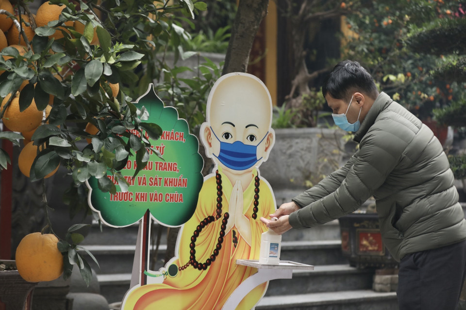 Debido a la pandemia del COVID-19, los visitantes a las pagodas realizan desinfección de manos (Foto: VNA)
