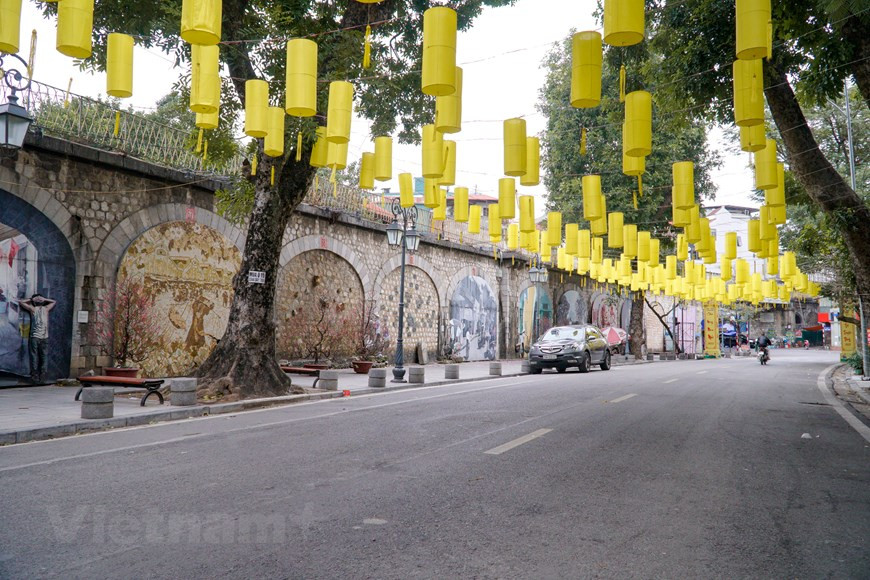 Esta mañana, la calle mural de Phung Hung está vacía. A diferencia de los días normales cuando la gente está ocupada y abarrotada, se disfruta del aire fresco y tranquilo del primer día del Año Nuevo Lunar. La calle de Phung Hung desemboca en el tradicional mercado de Dong Xuan, el mayor de su tipo en Hanoi, y está previsto cerrarla al tráfico para que acoja diversas actividades culturales y juegos populares. Inscritas en arcos abovedados, las pinturas ofrecen un singular soporte a la línea ferroviaria que pasa por encima, pero ni el ruido de los vagones distrae a los hanoienses de la nueva prenda que vino a embellecer sus vidas. (Fuente: Vietnamplus) 
