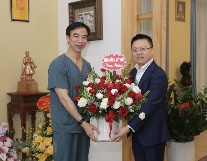 El miembro del Comité Central del Partido Comunista de Vietnam y director general adjunto de la VNA, Le Quoc Minh, felicita al director del Hospital Bach Mai, Nguyen Quang Tuan. (Fuente: VNA)
