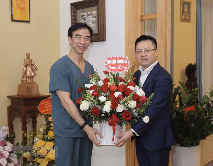 El miembro del Comité Central del Partido Comunista de Vietnam y director general adjunto de la VNA, Le Quoc Minh, felicita al director del Hospital Bach Mai, Nguyen Quang Tuan. (Fuente: VNA)