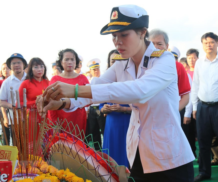 La teniente coronel Tran Thi Thuy, hija del difunto héroe de las fuerzas armadas Tran Van Phuong, colocó inciensos para rendir homenaje a los mártires. (Fuente: VNA)