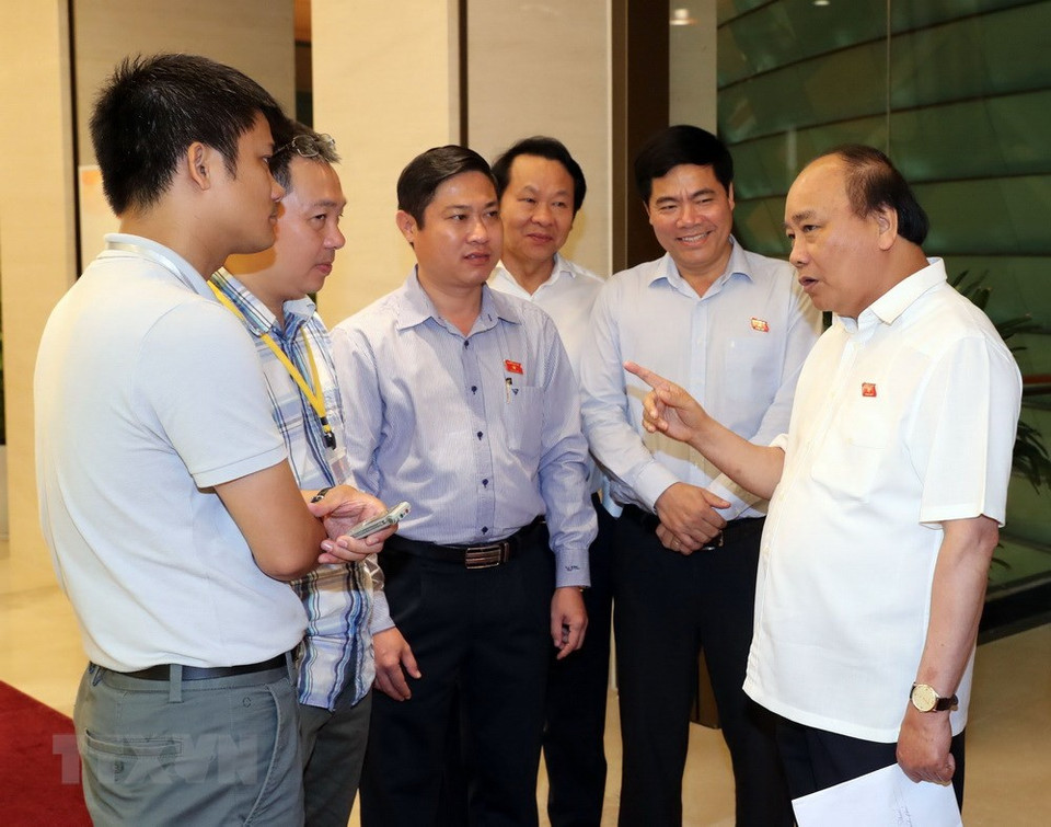 El primer ministro, Nguyen Xuan Phuc, conversa con diputados en el pasillo de la sesión (Fuente: VNA)
