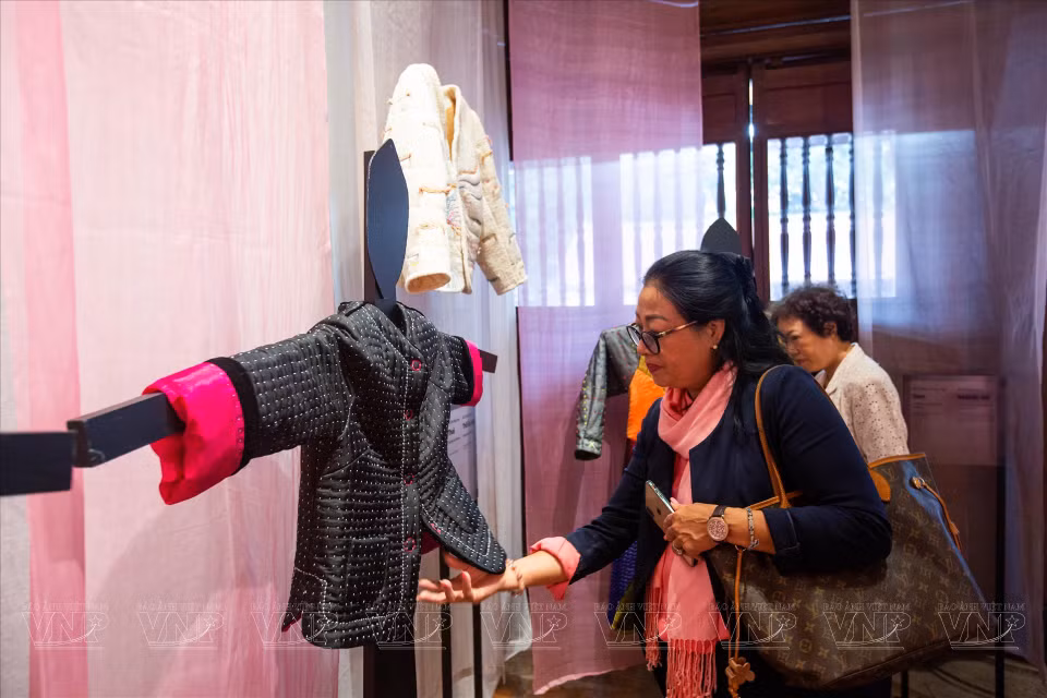Los turistas contemplan la camisa "Granos de Arroz" hecha de seda negra. (Fuente: VNA)