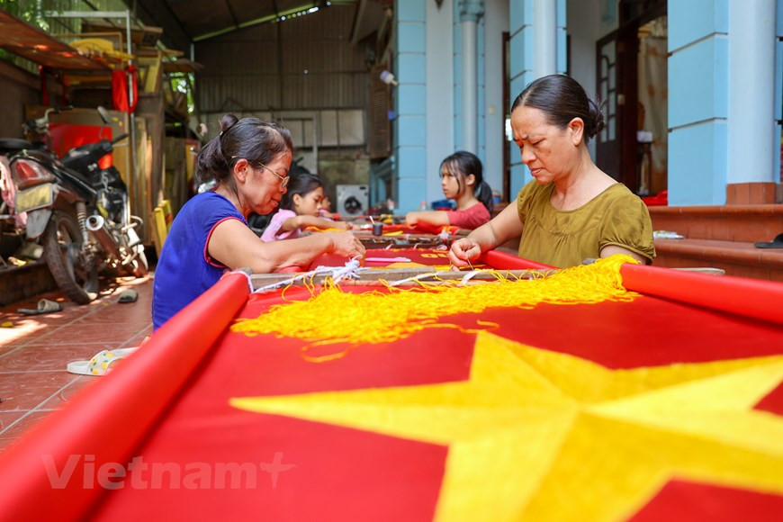 A lo largo de más de una década, la demanda de banderas nacionales ha aumentado notablemente, lo que genera más trabajos para la familia de Vuong Thi Nhung. Para completar una bandera bordada a mano, Nhung tarda de tres a cinco días, mientras que los artesanos menos profesionales pueden demorarse hasta una semana. Las puntadas deben alcanzar un alto nivel de precisión ya que las banderas se emplean en ocasiones formales. Por tal motivo, el costo de un producto hecho a mano es de aproximadamente 13 a 22 dólares según su tamaño, lo que supera muchas veces el precio de una bandera cosida a máquina. (Foto: Vietnam+)