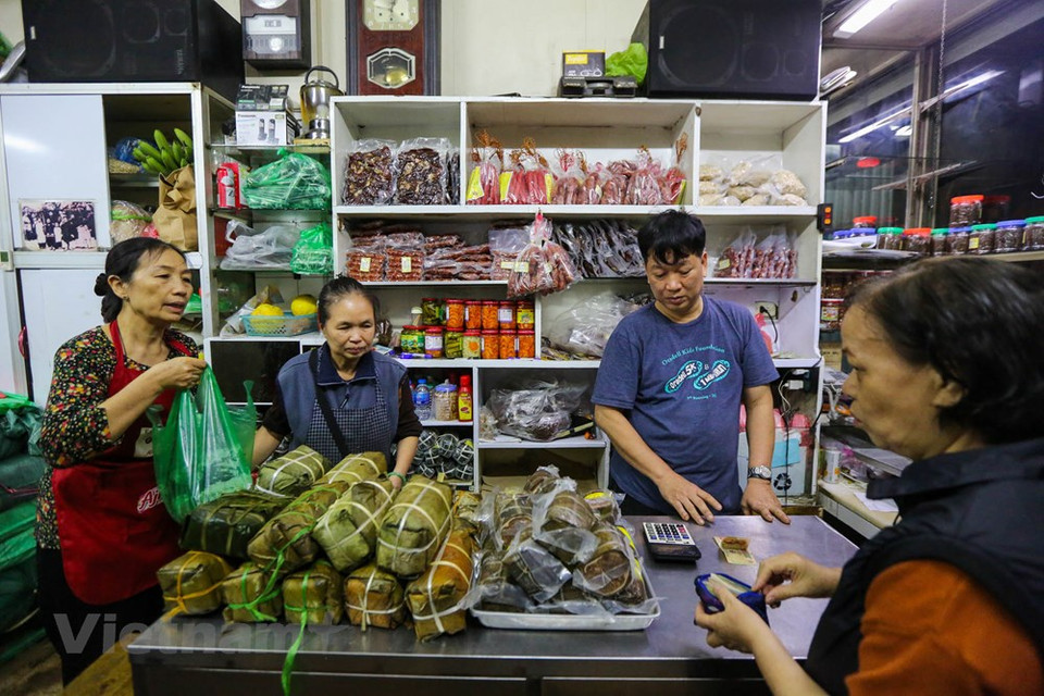 Muchas personas les gustan comprar Banh Chung (pasteles cuadrados de arroz glutinoso, cerdo y guisantes envueltos en hojas de banano) y Gio Cha (jamón o salchicha de Vietnam) en la tienda Quoc Huong. Los ingredientes necesarios para el Banh Chung son el arroz glutinoso, el frijol chino, la carne de cerdo grasa y pimienta negra, sal, a veces cebolla verde y salsa de pescado. Envuelto en un paquete cuadrado verde, el Banh Chung simboliza la Tierra, enfatizando también la procedencia de la naturaleza de sus diversos ingredientes el significado para los vietnamitas. Aparte de por la fiesta de Tết, Banh Chung también se consume todo el año como delicia de la cocina vietnamita. (Fuente: Minh Son / Vietnam +)