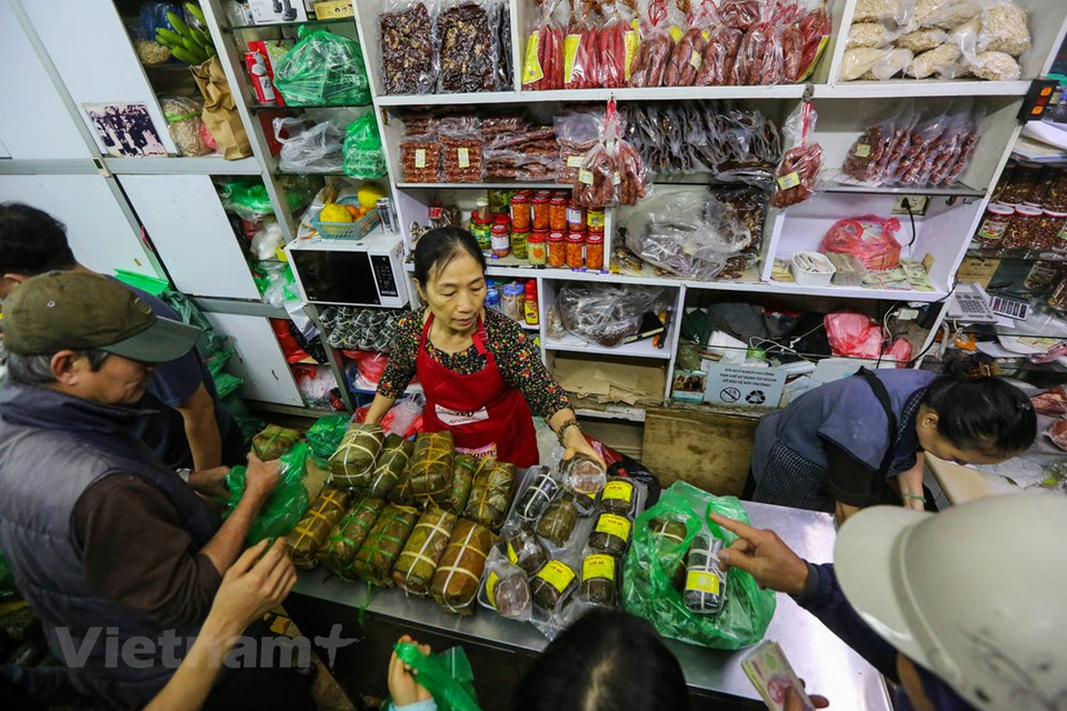 Según los clientes, en este momento del año pasado, muchas personas deben hacer colar y esperar para comprar un par de Banh Chung (pasteles cuadrados de arroz glutinoso, cerdo y guisantes envueltos en hojas de banano) y Gio Cha (jamón o salchicha de Vietnam. Considerado un elemento esencial del altar familiar con motivo del Tet, la elaboración y consumo de Banh Chung durante esa época es una tradición bien conservada por los vietnamitas. También hay variantes de Banh Chung sin cerdo para vegetarianos y budistas, como el Banh Chung Chay o el Banh Chung Ngot. Estas versiones se rellenan con melaza y azúcar morena, y para ellas a veces se mezcla el arroz glutinoso con gac, de forma que el pastel quede con una corteza roja más apetitosa. Fuente: Minh Son/ Vietnam+)