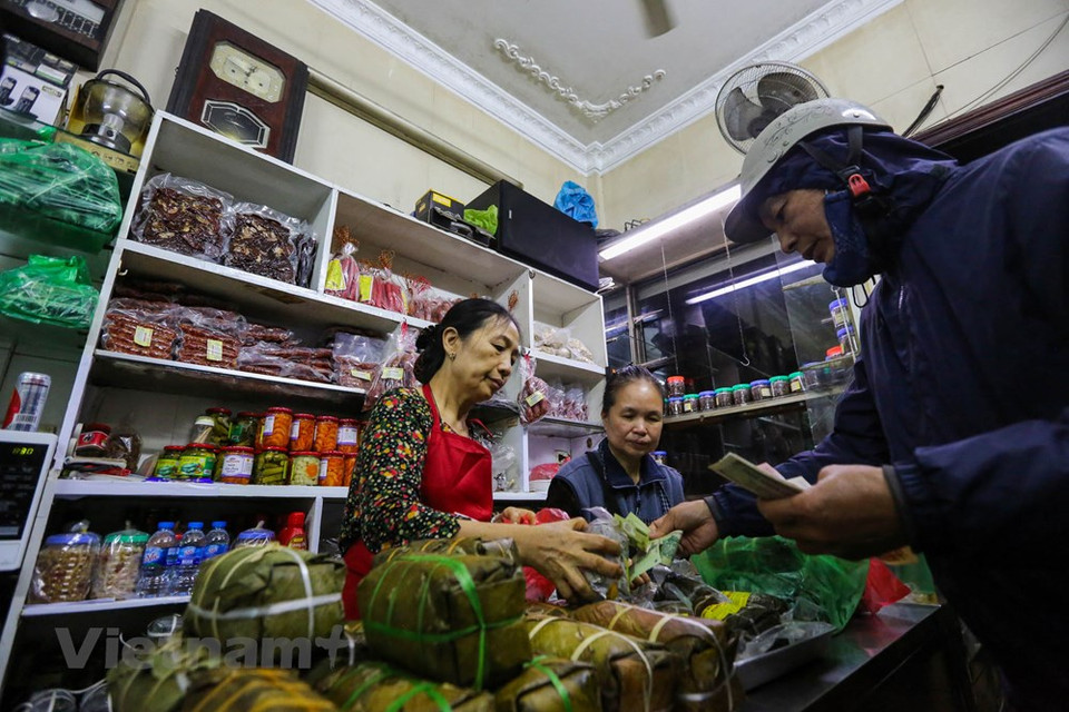 Dentro de la tienda, la propietaria Nguyen Thi Chan siempre está ocupado vendiendo Banh Chung (pasteles cuadrados de arroz glutinoso, cerdo y guisantes envueltos en hojas de banano) y Gio Cha (jamón o salchicha de Vietnam) a los clientes. Para las familias vietnamitas, el Banh Chung es un manjar indispensable en la bandera de ofrendas de culto a los ancestros en ocasión del Tet (Año Nuevo Lunar). Actualmente, ante el ambiente agitado de la vida, muchas familias optan por comprar el “Bánh chưng” ya elaborado en vez de prepararlo en casa. Debido a su larga historia y duradera popularidad, el Banh Chung se considera uno de los platos nacionales junto al Nem Ran y el Pho (Fuente: Minh Son / Vietnam +)