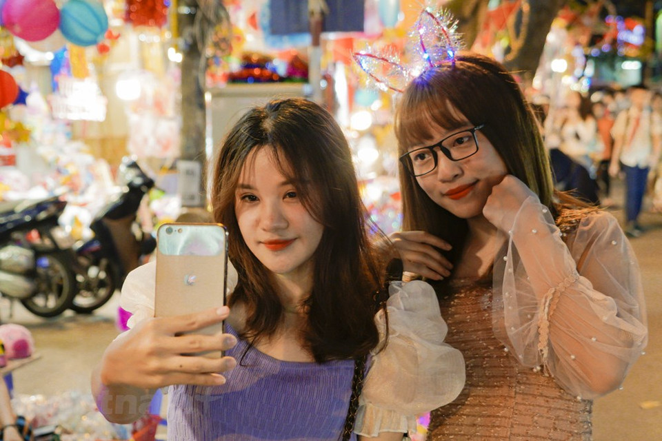 Una pareja joven saca fotos en la calle con linternas coloradas. (Foto: Minh Hieu / Vietnam +)