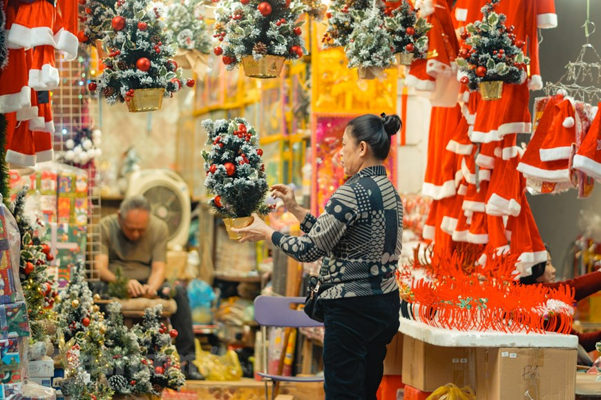 Según los pequeños comerciantes en la calle Hang Ma, hay un mayor número de clientes que compran este año adornos navideños que el año anterior. Estos productos se producen domésticamente y una parte se importa de China. Muchos árboles de Navidad de todos los tamaños fabricados por productores nacionales captan el interés de los clientes este año. Ese resultado se debe al mejoramiento de la calidad y la oferta diversificada de mercancías locales y sus precios razonables. Los artículos más populares son grandes pinos, coronas de puertas y símbolos navideños, cuyos precios varían de decenas de miles hasta millones de dongs, según el tamaño. (Foto: Vietnam+)