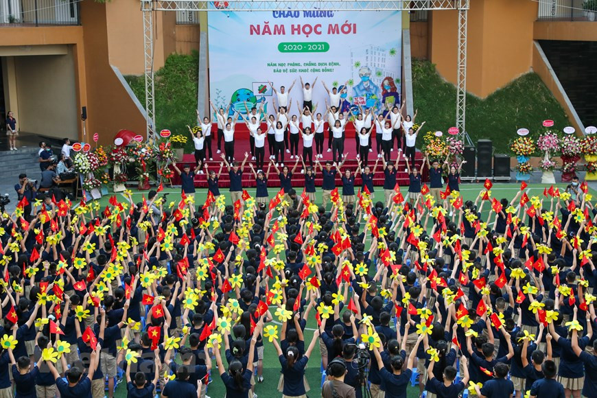 El Departamento de Educación y Capacitación de Hanoi ha exigido que las escuelas locales celebren ceremonias de apertura breves y solemnes para el nuevo año escolar para crear una atmósfera de júbilo para los estudiantes y garantizar la observancia de las medidas de control de la epidemia. Según el documento 2703 / SGDDT-VP del departamento, la ceremonia de apertura del año académico 2020-2021 debe llevarse a cabo en todas las escuelas de la ciudad en forma presencial el 5 de septiembre. Se instruye a las escuelas para que decidan el número de estudiantes que asistirán a la ceremonia en el patio de la escuela en función de su infraestructura para garantizar el distanciamiento físico. Otros estudiantes participan en el evento desde sus aulas. No se realiza ningún ensayo de ceremonia o desfile de nuevos estudiantes. (Fuente:Vietnamplus)