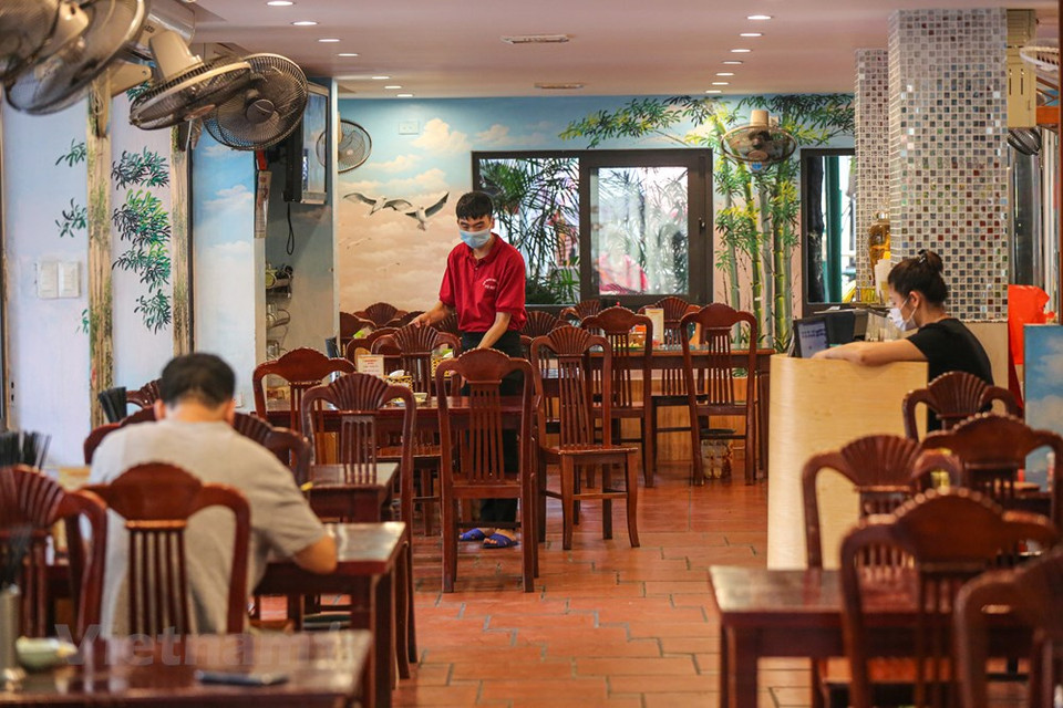Los empleados en restaurantes deben usar mascarillas durante el servicio, realizar la medición de la temperatura corporal a los clientes y limpiar las superficies de los objetos de frecuente contacto. La Organización Mundial de la Salud (OMS) reconoció al COVID-19 como una pandemia global el 11 de marzo de 2020. El coronavirus se transmite generalmente de persona a persona a través de las pequeñas gotas de saliva, conocidas como microgotas de Flügge, que se emiten al hablar, estornudar, toser o espirar. Se difunde principalmente cuando las personas están en contacto cercano, pero también al tocar una superficie contaminada y luego llevar las manos contaminadas a la cara o partes del cuerpo con mucosa. Su período de incubación suele ser de cinco días, pero puede variar de dos a 14 días. (Foto: Minh Son / Vietnam +)