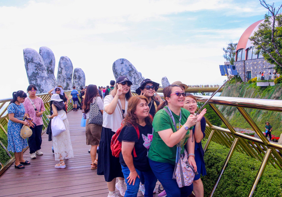 Turistas internacionales pasean con entusiasmo por el Puente Dorado, en el área turística Sun World Ba Na Hills. (Foto: VNA)