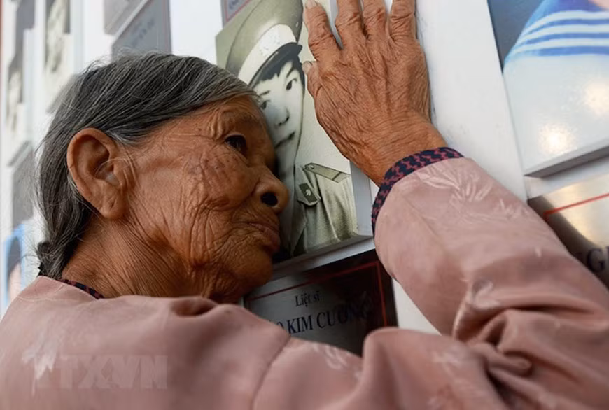 Ha Thi Lien, residente en del distrito de Can Loc, provincia de Ha Tinh, madre del soldado Dao Kim Cuong, besa la imagen de su hijo en la Zona Conmemorativa de los Mártires de Gac Ma, en Khanh Hoa. (Foto: VNA)