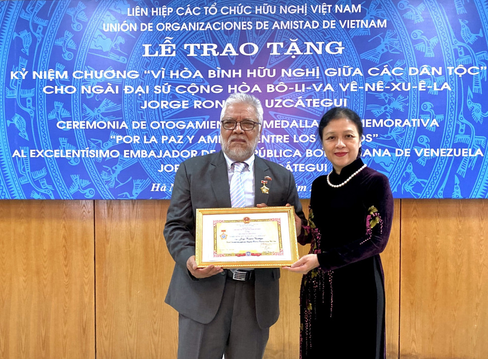 La embajadora Nguyen Phuong Nga, presidenta de VUFO, entrega la insignia al embajador, Rondón Uzcátegui (Foto: VNA)