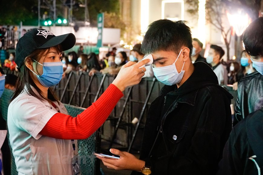 Una funcionaria médica mide la temperatura corporal de un espectador. (Fuente: VNA)