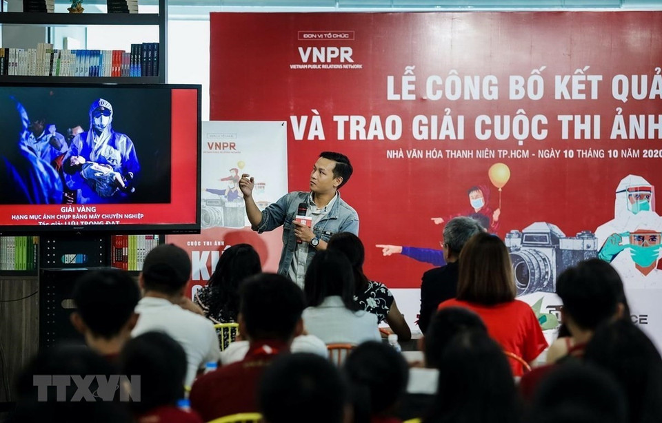 El reportero Luu Trong Dat de la VNA presenta la obra ganadora de la categoría “Foto captada con cámaras profesionales” en el concurso “Vietnam resiliente”. El certamen difunde imágenes sobre el pueblo vietnamita en la lucha contra la pandemia. (Foto: VNA)