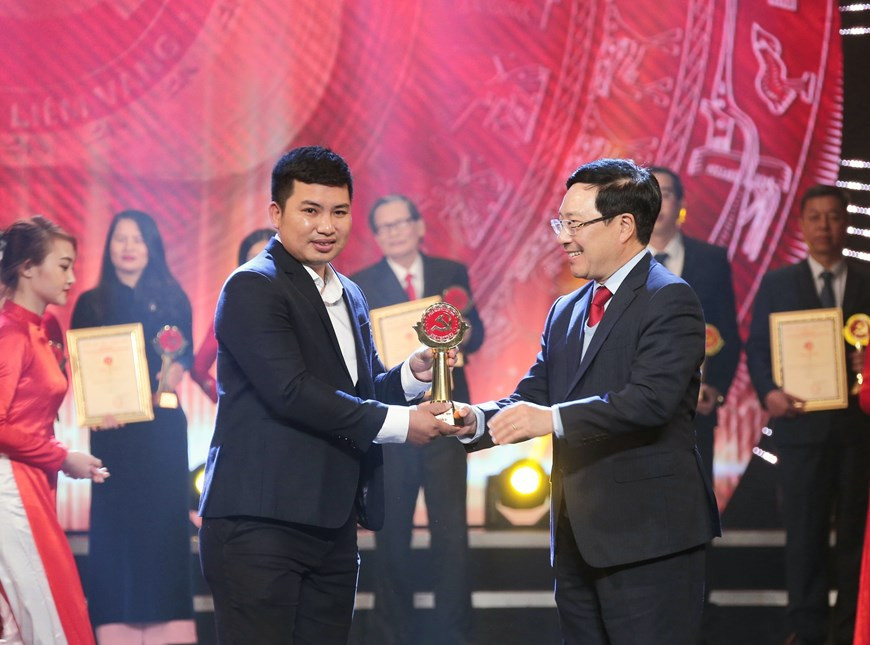El viceprimer ministro y canciller, Pham Binh Minh (D) presenta un premio B a Minh Quyet, fotógrafo de la VNA. (Fuente: VNA)