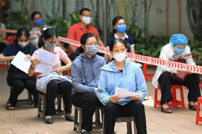 El personal médico del distrito de Hoan Kiem muestra la vacuna de Moderna a la gente con la que se le inyectará para que compruebe el producto. (Foto: VNA)