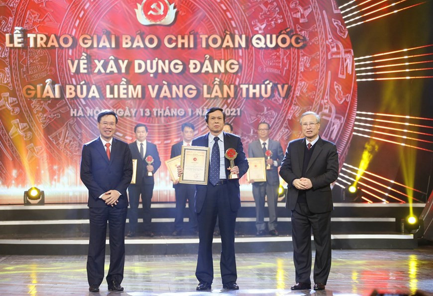 Tran Quoc Vuong (D) y Vo Van Thuong, jefe de la Comisión de Propaganda y Educación del Comité Central del PCV, presentan un premio A a Le Tri Dung, fotógrafo de la VNA. (Fuente: VNA)