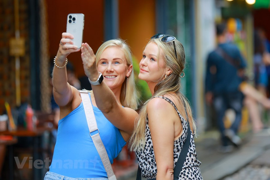 Mujeres turistas toman fotos libremente en las calles de Hanoi sin temor a condiciones inseguras. (Foto: Vietnam+)