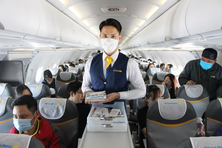 Auxiliar de vuelo sirve las porciones de comida (Foto: VNA)