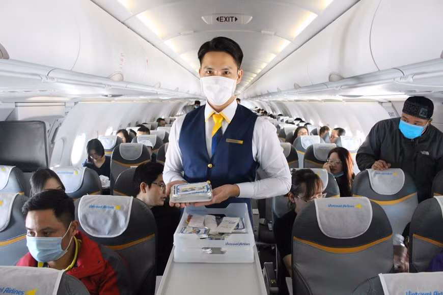 Auxiliar de vuelo sirve las porciones de comida (Foto: VNA)