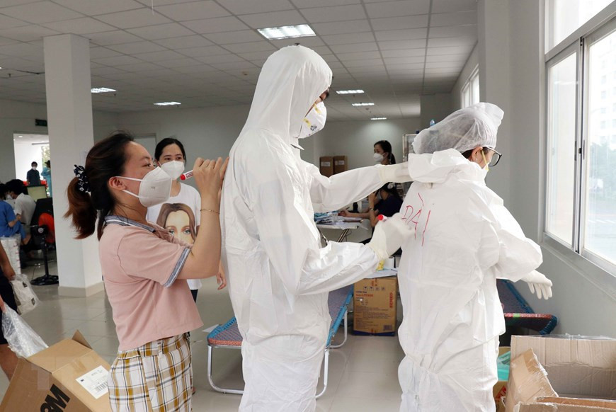 Médicos del hospital de campaña número 3 en la ciudad de Thu Duc escriben su nombre en la bata blanca para poder reconocerse entre sí. (Foto: VNA)