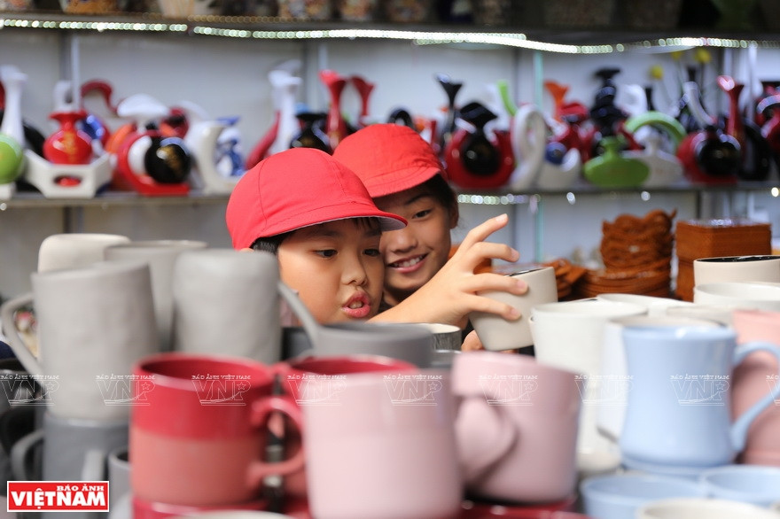 Dos niños procedentes de Japón seleccionan los vasos preciosos en el mercado de cerámica de Bat Trang, durante una acampada organizada por su escuela. (Fuente: VNA)