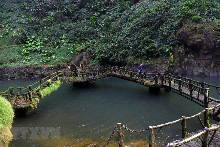 Un pequeño puente conecta las dos orillas al pie de la cascada, cubiertas durante todo el año de musgo. (Foto: VNA)