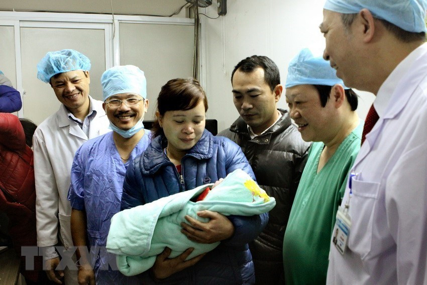 Nguyen Viet Tien, viceministro de Salud (camisa azul, derecha), quien operó directamente el caso de la primera gestación subrogada en el Hospital Central de Obstetricia, con el padre y la madre de la niña recién nacida en 2016. (Fuente: VNA)