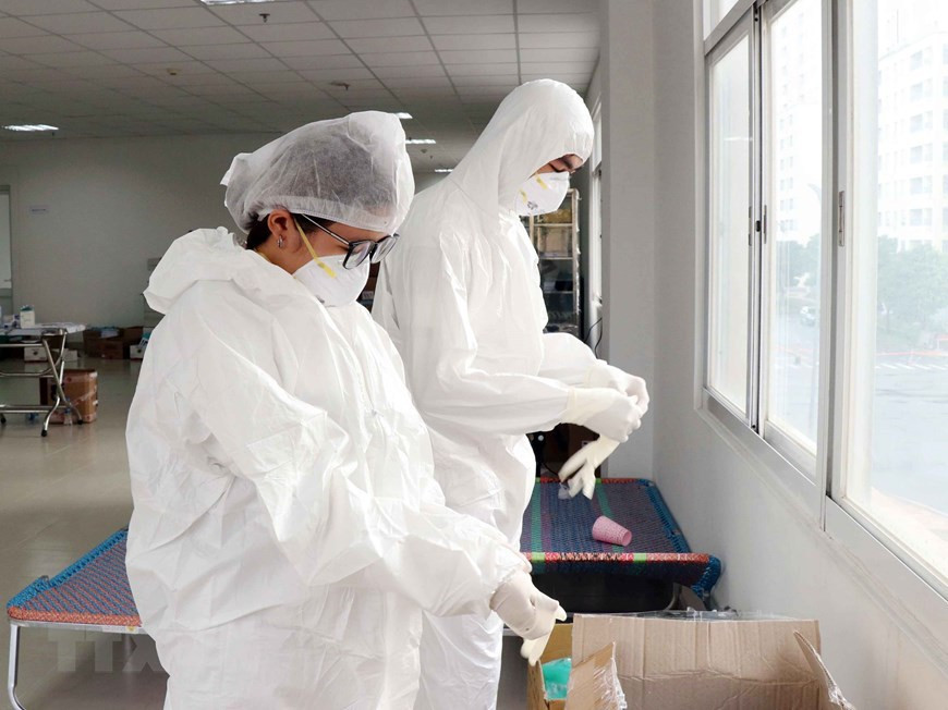 Cada miembro del personal médico viste el traje protector junto con tres guantes en cada mano antes de atender a los pacientes del COVID-19. (Foto: VNA)