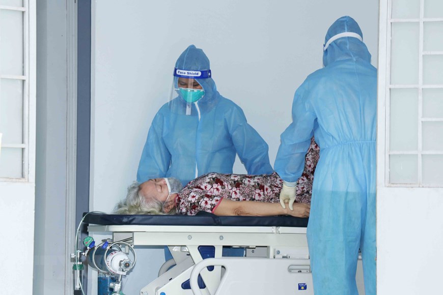 Médicos del hospital de campaña número 4 en la comuna de Vinh Loc B, del distrito de Binh Chanh, atienden a una paciente anciana. (Foto: VNA)