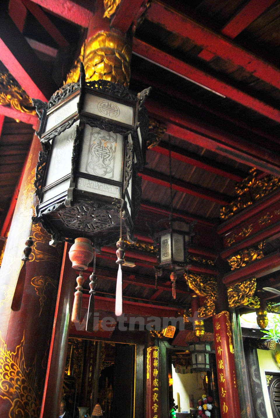 Farolillo tradicional colgado en el techo de madera pintada roja.