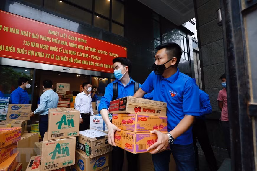 Los miembros de la UJCHCM y jóvenes del bloque de órganos centrales participantes en el transporte de productos de primera necesidad para apoyar a la provincia de Bac Giang en la lucha contra el COVID-19 (Foto: VNA)