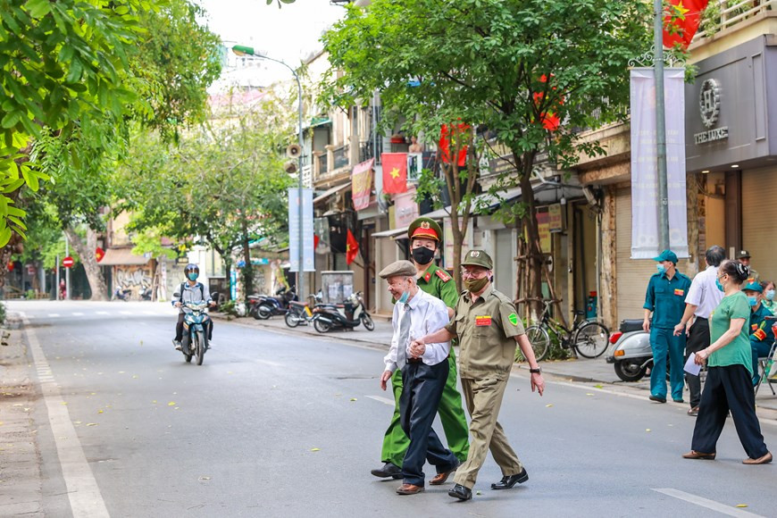 Las elecciones se celebran después del XIII Congreso Nacional del Partido Comunista, un evento de importancia estratégica para la renovación integral y el desarrollo rápido y sostenible del país en el nuevo período. En ese sentido, la selección de las personas calificadas a la Asamblea Nacional y los Consejos Populares constituye una tarea clave del Partido, el pueblo y el ejército en 2021. De los 866 candidatos, los electores seleccionarán a 500 diputados del Parlamento, tres mil 726 miembros de los Consejos Populares provinciales, 22 mil 952 de los distritales y 242 mil 312 a nivel de comuna. En la foto: Un policía y un miembro del equipo electoral llevan a Van Ca a su casa después de que el señor vota (Foto: Vietnam+) 