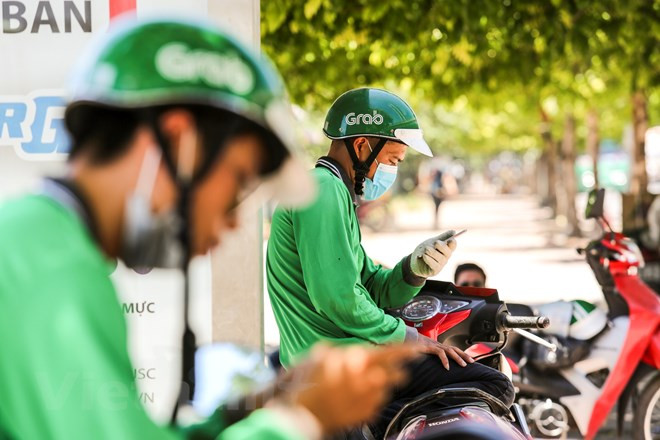 Bajo la sombra, los conductores de mototaxi esperan a sus clientes con paciencia (Fuente: VNA) 