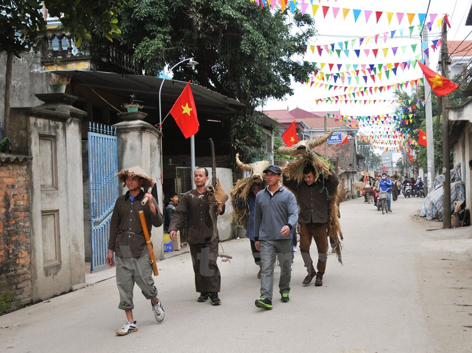 Un grupo de hombres se visten como agricultores de tiempos pasados, llevando herramientas de trabajo y animales, normalmente búfalo o vaca, hechos de pajas (Fuente: VNA)