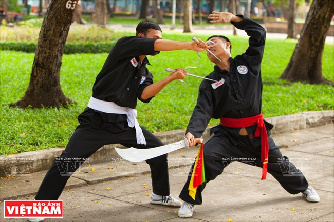 Dos alumnos Nguyen Van Trong y Nguyen Trung Nam presentan dos formas de combate de gallos con alfanjes y espaldas.