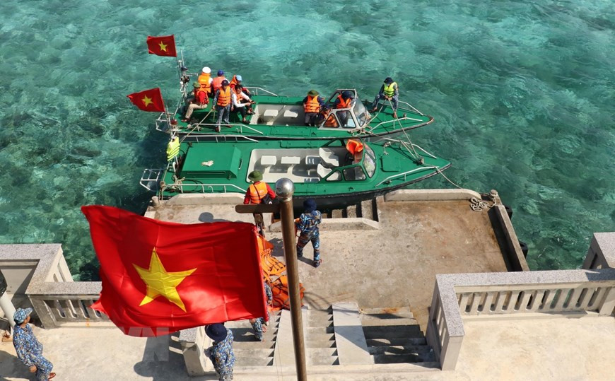 La bandera del país ondea cuando dos canoas del barco Truong Sa 571 atracan en la isla Co Lin (Foto: VNA)