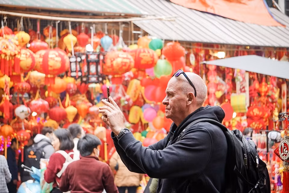 Un turista extranjero toma fotos sobre las preparaciones del Tet de los vietnamitas en el mercado de flores de Hang Luoc. (Fuente: VNA)