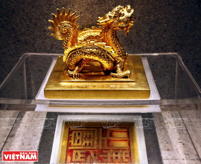 El sello de oro "Sac menh chi bao" pesa 8,3 kg, que fue lanzado en 1827 bajo el reinado del rey Minh Mang. Su perilla se hace en forma de un dragón que rueda y su cara se moldea con las cuatro palabras "Sac menh chi bao" en relieve. El sello se utilizó para la promoción de rango de los funcionarios civiles y militares, así como la concesión del título de las deidades y los seres humanos. Esta es la única exposición, que simboliza el poder de la dinastía Nguyen, con un valor especial en la colección de tesoros de oro de la dinastía Nguyen. Foto: Cong Dat / VNP