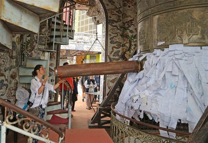 Una turista extranjera se encuentra junto a una campana de bronce dentro de la torre de siete pisos de la pagoda de Linh Phuoc (Fuente: VNA)