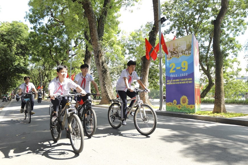 Los alumnos pasan junto a un letrero a orillas del lago Hoan Kiem. (Foto: VNA)